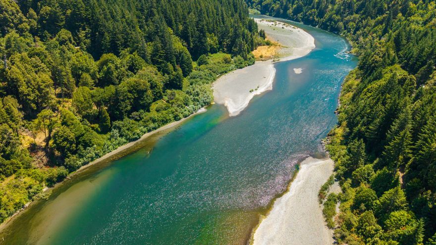 Off the grid & set in a stunningly beautiful location, this private, gated 5-acre property sits on the north bank of the Rogue River, is only 20 mins and 10 miles up the Rogue River from the popular Coastal Community of Gold Beach & only 35 minutes away from famous Agness Oregon (I.E. - If temperatures are 70 degrees in G.B. & 90 degrees in Agness - temps near perfect at this location in between at 80 degrees.)  Offering approximately 1,000 feet of river frontage, the land features multiple hourly-changing & breathtaking views of the Rogue River & surrounding mountains. A charming private beach & cove, along w/a fabulous year-round creek, provide both serene enjoyment & the potential for hydroelectric power thanks to its impressive water volume & pressure. There is an indication that the septic may be approved for up to 4 homesites & is rich w/mature timber, including towering Myrtlewood trees. Buyers to do all due diligence. The information is not guaranteed.