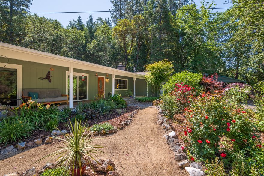 Tucked away on 2.61 gated, park-like acres, this beautifully maintained home offers space and privacy.  With a brand new roof and fresh exterior paint, the 3 bed, 2 bath home features hardwood floors, a spacious living and family room, and a primary suite with a massive walk-in closet. Step outside to the wraparound deck and enjoy the stunning, landscaped grounds. A detached guest room/rec room with it's own porch adds flexibility, plus there's a separate office, huge shop, and storage building. Gardeners will appreciate the greenhouse, fenced garden, and fruit trees. Two carports provide ample covered parking, including one for an RV. A peaceful, private setting with all the extras! Call for a tour today!