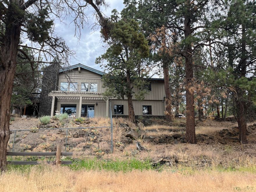 Rare development opportunity in NW Bend close to Riley Ranch Reserve! Home is up the hill with plenty of privacy and is on 1.26 acres. Lower parcel is .78 acre. This MidCentury home has great bones, vaulted ceilings with lots of nice wood details! Main level has primary bedroom, another bedroom, 1/2 bath, living room, dining room and kitchen. There is access to the large deck via the living room as well as the kitchen. The living room has a large wood burning fireplace. Downstairs has another two bedrooms, one bathroom and living area with fireplace insert. Living area has a slider to a small porch area overlooking the land and canal below. The home had water damage and is in need of extensive repair. Will not qualify for conventional financing. Plenty of opportunity to remodel the existing home or build new and develop the lots below!