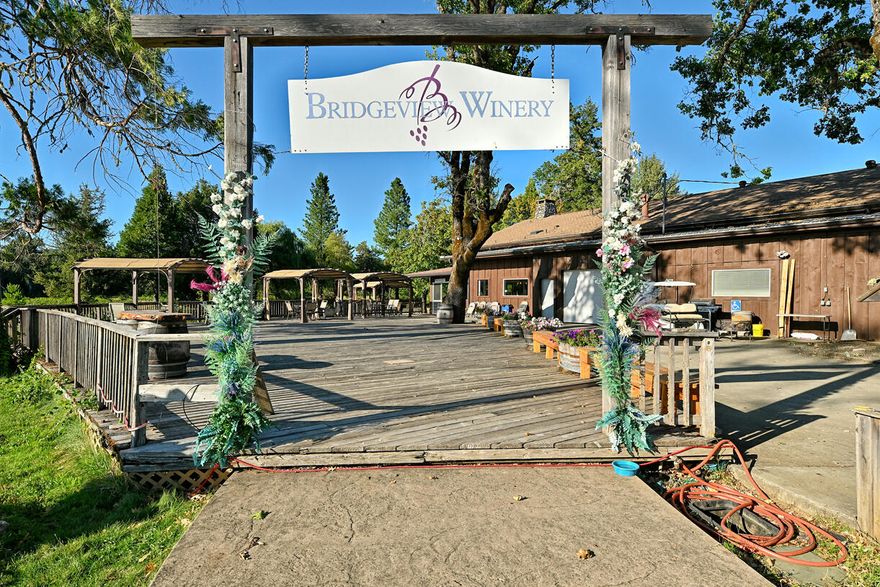 Bridgeview Vineyards & Winery - A Rare Southern Oregon Opportunity
Established in 1986, Bridgeview Vineyards and Winery has grown into one of Oregon's most recognized and successful wine destinations. This business and property come fully equipped with a 160,000-gallon tank capacity, established bulk wine sales, bottling and labeling facility, and a welcoming tasting room.
The sale includes not only the winery operation but also a charming two-story owner's residence overlooking ponds and vineyards, along with room for staff. Visitors from all over the world are drawn to Bridgeview for its breathtaking setting—picturesque lakes, decks over serene irrigation ponds with trout and swans, and sunsets that leave a lasting impression.
Beyond its daily winery operations, the property shines as an unforgettable venue. From weddings and concerts to community gatherings, the grounds are designed to host events of every size, complete with a staging area and ample scenic backdrops.