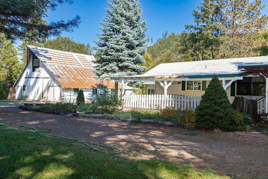 Unlock the homestead or business potential of this unique property! A historic 1909 two-story barn features cement flooring, a one-car garage, workbenches, and divided spaces, plus a 14' x 36' addition off the back. The property includes RV hookups (electric/water/septic), three chicken coops, a greenhouse, a potting shed, cold storage rock house, a large three-stall building, a 28' x 17' RV cover, and a well house. The 2,000 sq. ft. home blends stick-built and 1975 manufactured construction under a unified shingle roof. Enjoy a spacious primary suite with a walk-in closet, dual vanity, and a new low-step shower. Additional rooms include a second large bedroom, an office/loft space, and flexible living/dining areas. The country kitchen offers ample counter space and cabinets. A mudroom, laundry with ¾ bath, and a third bath (needs remodel) add convenience. Thompson Creek runs seasonally along the back border, and Lake Selmac is just two miles away. A divorce sale—priced to move!