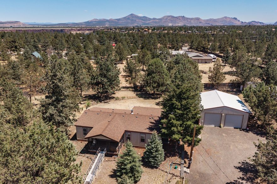 This 3 bedroom, 2 bathroom home is sited on over 1.5 acres of FULLY-FENCED and flat property and is ready for new owners. Recently updated smart kitchen appliances, including a touch-less faucet highlight the inside, while covered decks on the front and back provide more space to enjoy. There is a ramp to the home, and the primary bathroom shower has grip-assists with a low threshold for safe and easy access. Multiple convenient outbuildings are part of the package too, including a 1080 sq ft shop with 3 rollup doors, a workshop and additional storage via ladder access. A 3-sided RV carport provides year-round weather protection. There is a finished and insulated large shed that was used as a quilting room. A chicken coop and shed complete the property. You'll find peace and quiet-it is located at the end of a small cul-de-sac, and charm-there are flower beds, a small water feature, and even some pine trees!. Homeowners also get access to a horse arena, pool and discounted golf.