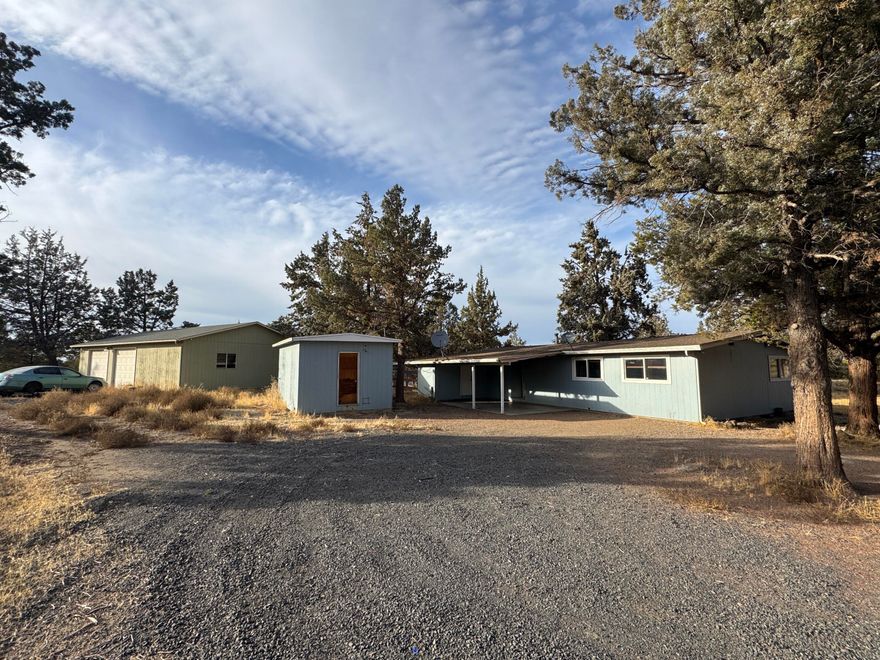 Discover this single-level home nestled in a highly desirable and quiet neighborhood—just minutes from town, Cline Falls State Park, the Deschutes River, and Eagle Crest Resort, where you'll find fine dining & 3 golf courses.  Situated on a fenced 1.13-acre corner lot toward the back of the subdivision, this property offers privacy and peaceful enjoyment of the outdoors. The home features a bright, open, and vaulted floor plan with a spacious wraparound deck perfect for entertaining or relaxing. Additional highlights include a newer mini-split heating and cooling system and a cozy wood-burning fireplace. This property also boasts nice outbuildings, including: a shop with a dedicated workspace, a large powered storage building—ideal as a hobby room, gym, studio, or man cave, a dog kennel, & a covered carport. With its great location, functional layout, and usable space, this home is full of potential. Bring your vision and creative ideas to make this unique property truly your own!