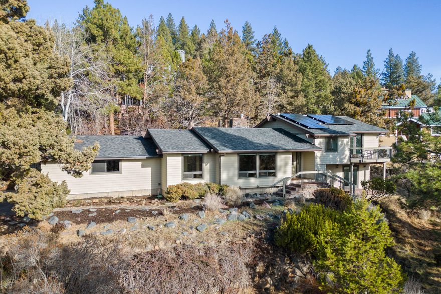 Classic West Hills home on a .42 acre lot with room for an ADU. Living room/dining room feature open beam ceilings, lava rock wood burning fireplace and panoramic views. The great room has a thermostat-controlled gas stove, picture windows and skylights.  Primary bedroom suite has a balcony, views of Mt. Bachelor, dual sinks, soaking tub and a walk-in shower.   The lower level with private entrance has 2 bedrooms, wet bar and a full bath perfect for guests or a Type I STR (short term rental) as an owner-occupied resident.  Roof was replaced in 2019 and solar was added.  Huge crawl space for storage.  There is a large 2 car garage with a work bench, storage cabinets & a storage shed.