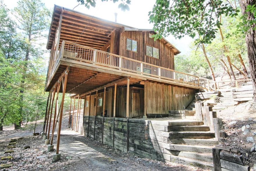 Not Your Average ''Cabin in the Woods'' Modern rustic retreat on 6+ forested acres adjacent to expansive public lands. 3 thoughtful levels. Main space sits at ''treehouse'' height, elevating your experience to serene views. Cathedral-style covered deck feels like an outdoor sanctuary, relax or entertain in any season. Updated kitchen, fit for a chef, opens to dining & living areas & features a generous pantry w/ abundant shelving, freezer & second fridge. 
This level also has 1/2 bath & three access doors to wrap around deck. Upstairs are 3 cozy bedrooms, including one w/ private deck & direct access to the updated bath. Finished daylight basement offers flexible space for guests or family w/ large bonus room, bedroom, full bath & laundry room, complete w/ a laundry chute from the top floor. 2 water heaters (1 solar), full house fan system, heat control in each room & generous attic space. Circular drive, equipment shed & easy ramp entrance that allows direct car access.