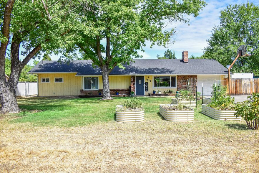 Beautifully updated single story home has contemporary touches, vaulted ceiling, open concept floor-plan, covered back patio, and extra wide driveway for vehicles or RV! Huge Primary bedroom has patio access, walk in closet, and a sumptuous en-suite bathroom with a walk-in tile shower, AND a roomy soaking tub! The kitchen includes a gas range/oven, a well appointed island, and lots of storage. Extra space off the kitchen is currently being used for an artist area, but could also be space for office, reading, gaming, or 2nd common area. Main living area has wood burning fireplace, and lots of natural light. 2 guest bedrooms, and an updated guest bath, complete this move in ready home. Single car garage has more storage, and access to side yard. Fully fenced back yard includes a shed. Currently, the raised garden beds are in the front yard for more sun. Showings by appointment only. Floorplan and measurements included online.