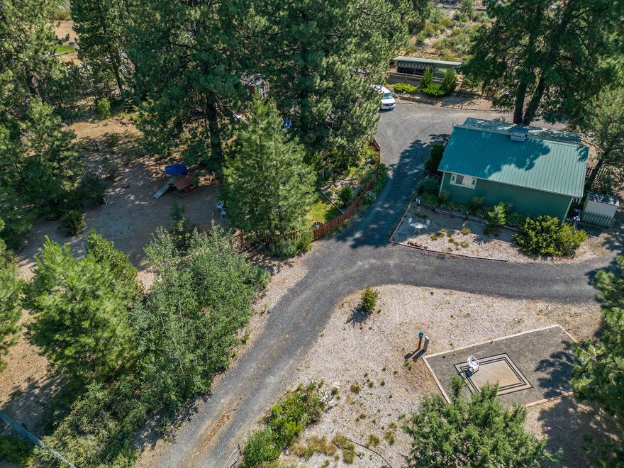 Versatile and charming, this lovingly maintained small acreage property tucked among the trees on a corner lot in Deschutes River Woods, truly has it all. Here, a quaint 2 bedroom (plus) manufactured home with a new roof, new windows, full air conditioning, and spacious kitchen are just the beginning for this turnkey opportunity. The well-insulated and fully finished 30x30 shop building with electric radiant floor heating is currently used for the property's successful dog training business, and includes custom kennels and a fenced outdoor dog run for exercise and training. The shed and greenhouse are set among towering pines for ample shade, and the raised garden beds are tucked aside a lovely outdoor seating area with a water feature for ambiance. Horses are welcome, chickens as well! Fully fenced with an electric front gate for privacy, a full gravel turn around for trucks and guests, and a fully loaded RV pad with hookups, this truly is a perfect place to call home.