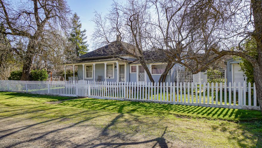 A 1910 Victorian Queen Anne Cottage sits at 104 S 1st. St. on a flat .34 acre lot located in a great location near the heart of downtown Talent. Open the white picket fence and enjoy all this home has to offer. The classic covered front porch and swing beckon you to enjoy life. This 1128 sq ft, 3 bedroom, 1 bath home comes with high ceilings, a cozy living room and vintage wood burning stove. Off the living room is a dining area with built-in dish cabinet and two windows looking out to the back patio. The large mudroom comes with a built-in pantry plus a washer and dryer. The kitchen includes a vintage wood burning ''Red Mountain T'' stove. From the kitchen access the covered back porch and enjoy a cup of morning coffee. The backyard has a wonderful garden space with a variety of fruit trees and flowers. Alley access to back of property. 4 outbuildings include woodshop, 2 sheds, and a large storage room. This property is unique and has many possibilities.
