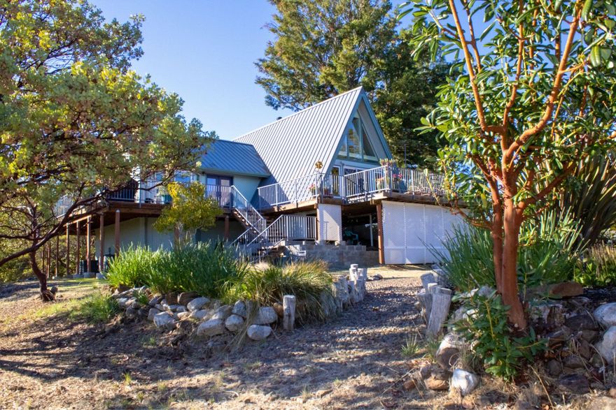 COUNTRY SETTING CITY CLOSE! This well maintained Gem is sitting on over 5 beautiful acres with stunning views from the large wrap around porch. It's a dream A-FRAME home featuring 3 bedrooms, 2 baths plus 367 sqft of additional finished basement space (above ground) with exterior access. The open concept center island kitchen offers newer cabinetry, ample storage, a pantry and plantation blinds. Main level: living room with built in cabinets to maximize space, new certified wood stove, primary bedroom, bathroom & laundry room. Two bedrooms up the spiral staircase plus walk in attic (bonus room) and second bathroom. Freshly painted exterior in 2024, new hybrid water heater installed in 2024, workshop area in garage, chicken coop, RV parking, a variety of trees & a seasonal creek + endless possibilities. You've got to tour this one of a kind, property in person.