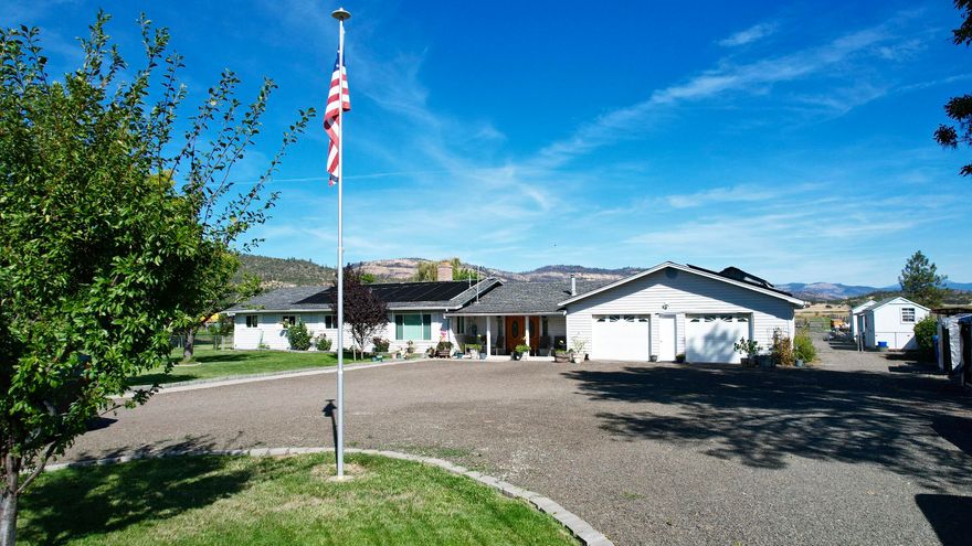 Enjoy country living with stunning mountain views from this versatile 4.92-acre property featuring a 3-bedroom, 2-bath, 1,694 sq. ft. home with a sunken living room, family room with fireplace, newer appliances, granite kitchen countertops, tile backsplash, hardwood flooring in kitchen, pantry, and a large concrete patio overlooking an in-ground solar-heated pool. Additional amenities include a detached office/storage space, an oversized 2-car garage (868 sq. ft.), a mini barn, a 30x40-animal barn with stalls and hay loft, several outbuildings, raised garden beds, greenhouse, and fenced and cross-fenced areas with invisible fencing in the front yard—ideal for animals, gardening, or simply enjoying the peaceful setting.