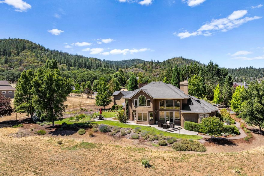 This is the reason why people want to live in Southern Oregon; this Pagnini-built country estate is located at the end of a private drive minutes from historic Jacksonville on 2 acres, providing a comfortable quiet country feel w/ the conveniences of town. Lots of room for hobbies w/ a semi-detached finished 3+ car garage, RV parking, & 770 sf guest quarters w/ a full bath & kitchenette. The Tuscan style home features an open floor plan w/ soaring ceilings & lots of natural light, w/ amazing mtn & valley views. Downstairs has chef's dream kitchen w/ sub zero fridge, double ovens plus convection oven & Wolf gas range & warming drawer, a huge island, & a butler pantry w/ a wine fridge & walk in panty. The downstairs also features both informal & formal dining areas, & the LR has a gas f/p w/ built-ins. The primary bedrm is on main floor & features a gorgeous ensuite bath & an office w/ built-ins. Two additional primary bedrms are located upstairs. Well produced 11.4 GPM when last tested