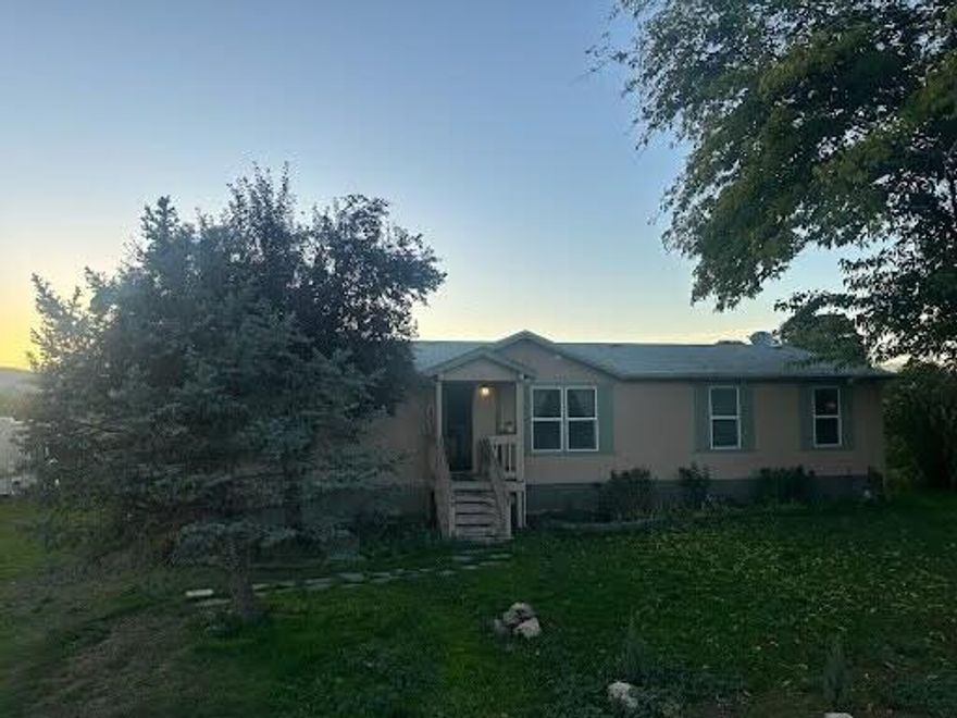Incredible value here. Perfect for a first-time homebuyer or investor looking for a little land close to town yet with a peaceful country feel. This affordable, financeable double-wide 2004 manufactured home on its own foundation that sits on a large .31 acre lot with nothing behind it, which gives it incredible mountain views. It's in great condition and features a split bedroom floor plan, 4 true bedrooms, vaulted ceilings, bamboo flooring, a newer back deck, a recently installed heating and air system, newer well pump/pressure tank, newly serviced water filtration, mature landscaping, and more. There's plenty of extra parking with space for an RV or future shop, plus a nice-sized shed for extra storage. Conveniently located near town but tucked away for privacy, this home offers comfort, space, and lasting value.