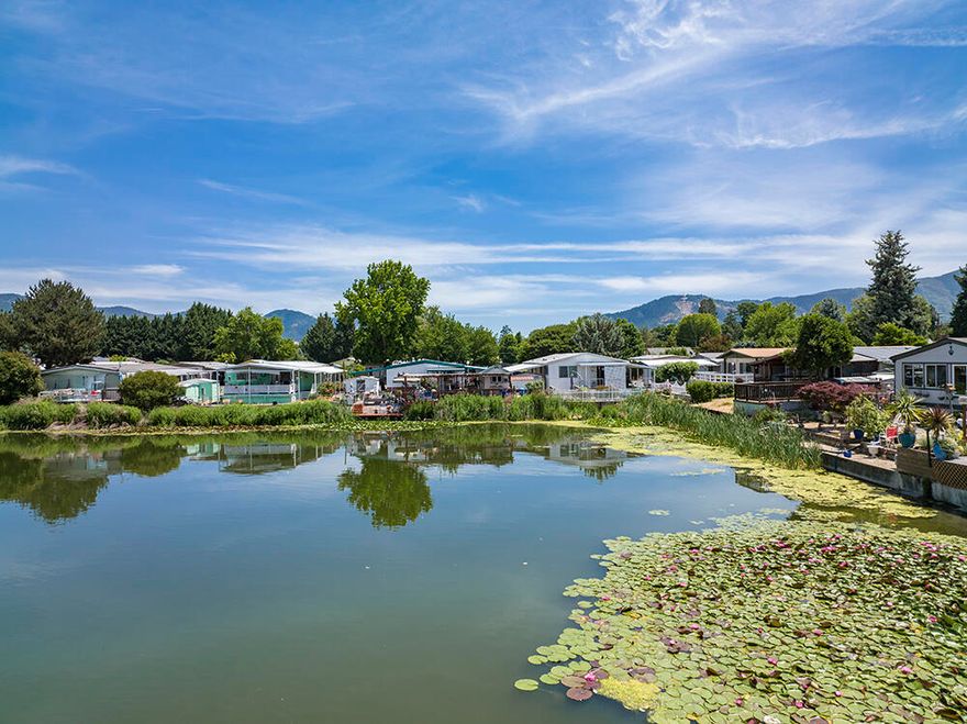 Spacious, well-cared for 3 Bed, 1.5 bath manufactured home in 55+ park with a view of the Rogue Lea Estates stunning Lake. This bright and inviting home features many upgrades, such as, a brand NEW ROOF, new double pane windows, recently remodeled bathroom, complete with a built in shower seat! The outside of the home has a lovely wrap-around porch with Trex Decking, easy to maintain, mature landscaping, with an additional patio in front of the peaceful and captivating lake, for outdoor living and entertaining. Carport is conveniently adjacent to the backdoor ramp for easy entry into home and there are 2 large storage sheds. This is a must-see property in a picturesque, quiet park! Seller willing to Credit Buyer $1500 dollars towards Closing Costs, Escrow Fees or Space Rent.