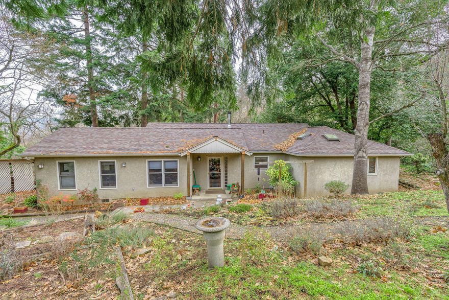 Enjoy this scenic and secluded setting offering 2 homes on 1 tax lot. The single level main home is 1553 square foot with 2 bedrooms, 2 bathrooms, and a large office. The wooded setting with Wrights Creek running through it provides the serenity of county living within the city limit. The light travels inside the home's large windows and skylights. Fir floors and a nice use of wood throughout the home accent the home's openness. The cozy wood burning stove provides a nice backup to the hybrid electric/gas HVAC system. Newer blinds installed in all of the rooms. The roof was replaced 2 years ago. The front yard is landscaped with a drip system. This is a well maintained home. The apartment over the 2 car garage is a nice 1 bedroom, 1 bathroom home. It's in great shape and currently has a long term tenant. This wooded paradise could be yours.