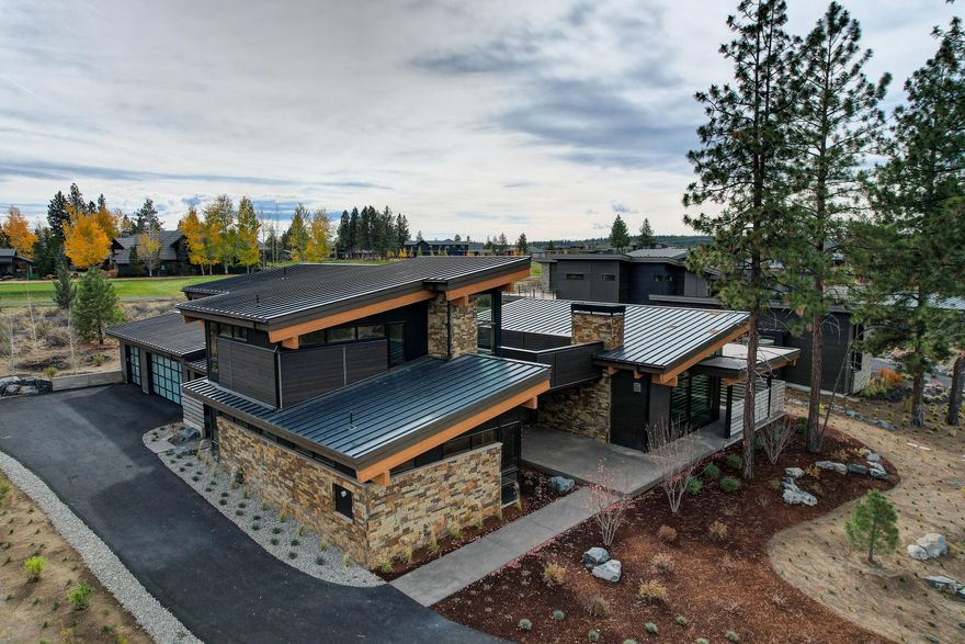 This mountain modern masterpiece by BendTrend Homes fuses quality and luxury with a functional design that leaves nothing behind. There are three suites on the main level plus a den and powder room. The 4th bedroom, bath and bonus room are upstairs providing a separate haven for guests and hang time. The progressive chef's kitchen is highlighted by white upper cabinets and walnut on the lowers, white quartz counters, a large island with eating bar, and high-end Jenn-Air appliances. The primary suite with spa-like bath features a freestanding soaking tub and tiled walk-in shower. Exceptional outdoor entertaining spaces include a covered terrace with outdoor fireplace off the great room, a private courtyard on the golf course side of the home, and a second-level roof top deck. This home backs to the Broken Top golf course and the Cascade Highlands Trail for biking & hiking is out your front door. This is a stunning addition to the Tetherow community.