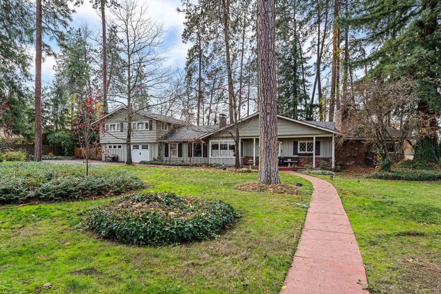 A secluded retreat offering privacy on an estate-sized lot, close to Jacksonville. Tree-lovers paradise with an assortment of majestic trees including Cedar, Pine, Sequoia, Redwood, Fir & Oak. Enjoy the rural lifestyle, yet close to shopping, restaurants and services. The dramatic mountain lodge style living room presents a vaulted timber-beamed ceiling & a huge rock fireplace. The modern, country kitchen has updated appliances, granite counters & a breakfast nook. The main floor 580 sq-ft primary suite features a pine ceiling, dual vanities, double closets, tile shower & separate tub. Also on the main level is a den/library with floor-to-ceiling built-in cabinets & a 2nd fireplace. The upper level has 2 additional bedrooms with cedar beamed ceilings and a full bath. Gleaming wood floors are throughout. The oversized 635 sq-ft garage has a large workshop area. Rounding out the grounds are a mini-orchard with pears & apples, raised beds, RV carport, storage shed & viewing deck.