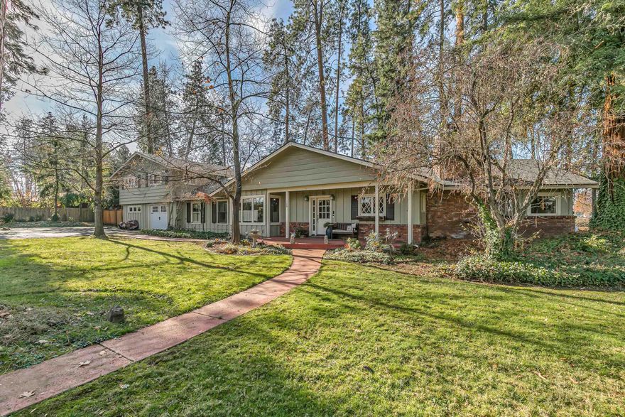 A secluded retreat offering privacy on an estate-sized lot, close to Jacksonville. Tree-lovers paradise with an assortment of majestic trees including Cedar, Pine, Sequoia, Redwood, Fir & Oak. Enjoy the rural lifestyle, yet close to shopping, restaurants and services. The dramatic mountain lodge style living room presents a vaulted timber-beamed ceiling & a huge rock fireplace. The modern, country kitchen has updated appliances, granite counters & a breakfast nook. The main floor 580 sq-ft primary suite features a pine ceiling, dual vanities, double closets, tile shower & separate tub. Also on the main level is a den/library with floor-to-ceiling built-in cabinets & a 2nd fireplace. The upper level has 2 additional bedrooms with cedar beamed ceilings and a full bath. Gleaming wood floors are throughout. The oversized 635 sq-ft garage has a large workshop area. Rounding out the grounds are a mini-orchard with pears & apples, raised beds, RV carport, storage shed & viewing deck.