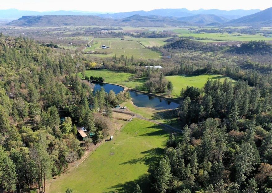 Tremendously loved, well-maintained property.  Close to town, wine tasting a stone throw away, tranquility + opportunity for a sanctuary/ family compound. Beautiful meadows, park-like forest, 52+ acres w/ BLM on 2 sides. Nature provides water to seasonal creeks, lovely ponds, 3 springs, 2+ acres irrig. Move-in ready property like this is a GIFT. 3 gated entries: #1= 1642 SF 3 bd, 2 ba home & garage. Huge boulders for scenic setting. #2 Cozy, clean 3 bd, 1 ba MH w/garage, water storage, meadow view, incredibly private setting. #3 winds along to a 32x72 detached accessory structure w/ 2 full baths, laundry & loft overlooking pond & campground w/BBQ, horseshoe pits, playground. Each structure has private well. Ride horses, raise livestock or grow crops. Barns, good fences, corral, separate pastures, RV parking. 2 tax lots, WR/EFU zoned. Dead-end road, feels PRIVATE yet ''a world away'' but only @14 miles from Costco & Medford Int'l Airport. 2nd home for guests, family or rental income.