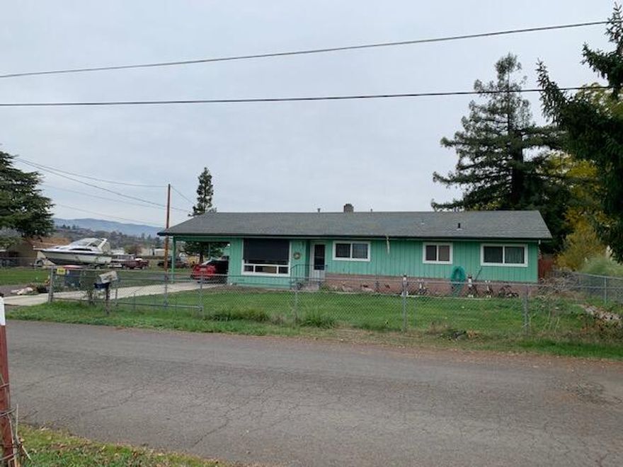 Shop Enthusiasts! Not one shop but two on .77 of an acre! The larger shop (approximately 30 X 40, per seller) has heat and a room that could be an office or hobby room has a bathroom complete with a shower.  Smaller shop (approx..600- 700 SF, per seller) has a storage area with shelving, heated and large doors that roll side to side.  Both shops have 220.  Home has 3 bedrooms, 2 baths (one with tub the other has shower), galley kitchen with a dining area, laminate flooring, large living area, washer and dryer, car port, covered patio, 2 wells, one for house use with a newer pump and the other well for irrigation.  This property has an RV Dump and RV Hook Ups. Also, there is plenty of room to park all your recreational vehicles.  This property has great possibilities.  Buyer to do their own due diligence.  Call for your personal tour!