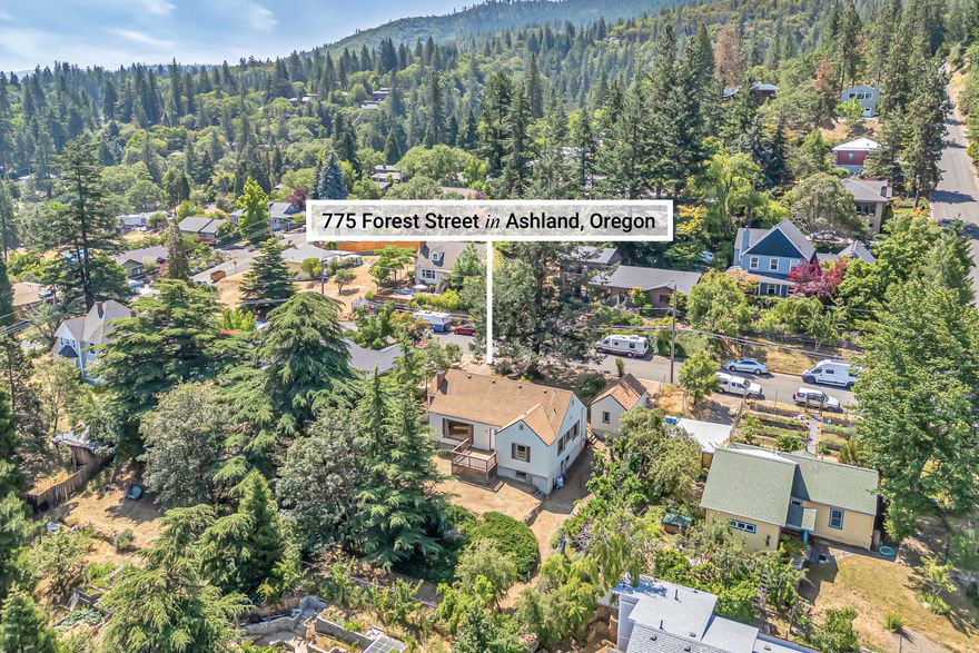 Charming mid-century mountain view home located above the boulevard just four blocks from Glenwood Park and Southern Oregon University!  Main level with solid oak hardwood flooring, curved moldings, large picture windows, wood burning fireplace with brick surround, composite view deck, and covered front porch. Kitchen with stainless electric range oven and dishwasher, refrigerator, solid surface counters, and double sink overlooking front yard. Two main-level bedrooms with closets and one full bath with tiled floor and tub shower surround. Full 1,188 SqFt basement with poured concrete foundation, daylight windows, washer and dryer, utility sink, and workshop recreation area - potentially suitable for conversion to guest quarters or primary suite. Spacious 0.24-acre lot with mature trees, sunny gardening areas, detached one-car garage, and gently sloped backyard. Property shall be sold ''As-Is'' in present condition.