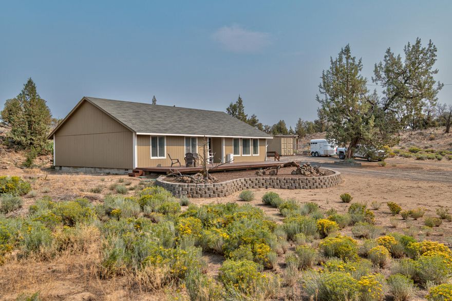 Situated in the heart of Central Oregon countryside on the outskirts of Bend, this 5+ acre horse property is the perfect spot to call home. Tucked into the rock outcroppings & ancient Junipers, this classic ranch style home features a huge front deck for entertaining & watching the sunset. Inside you'll find a main family room off the entry, dining area, 2nd living space off the kitchen. Kitchen features laminate flooring, breakfast bar seating, tiled counters, large walk in pantry, & plenty of counter/cabinet space. Extra wide hallway leading to the bedrooms is perfect for a small open office space/home school. Primary bedroom has lg walk in closet & adjoining bath features shower/bath combo plus basin style sink w/tiled counters. Two other spacious bedrooms share a full bath as well. Outside you'll find plenty of space for RV parking, all your toys & critters, plus fully fenced paddocks w/loafing sheds. New interior & exterior paint, deck just refinished, move in ready. Don't miss!