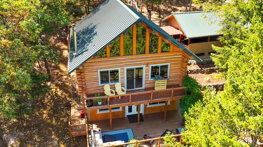 This pristine Log home sits on 5 private acres nestled in the sought after Griffin Creek area. The home is surrounded by abundant wildlife, trees & wild flowers. From the three decks you can take in the sprawling Mountain views all day and watch the glistening city lights at night. The bright, open-concept layout invites natural light and scenic views, while vaulted ceilings, wood textures, and certified wood stove create a warm, welcoming atmosphere.  Enjoy maple kitchen cabinets, Corian counters, custom light fixtures & a metal roof. Flooring includes Italian ceramic tile, pine plank & hickory flooring & Armstrong Laminate.  Recent updates include a 20x24 Garage/shop built in 2022, HVAC, windows, doors, Trex decking, gutters & more.  The well provides 7-10 GPM and there's an additional in-ground 1000 gal holding tank. There's also an artist's studio mini cabin.