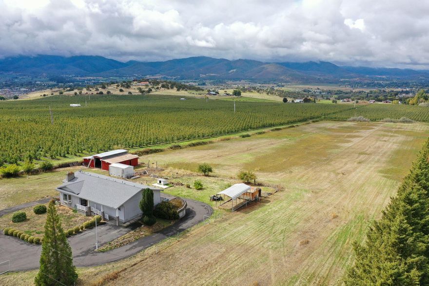 This country property has a 2016 sq. ft home and sits on 5 irrigated acres with views.  There is a separate of 2.51 acre irrigated tax lot also included for a total of 7.51 acres.  The home has a deck which gives you beautiful views.   Inside the home you will find a large living room, plenty of windows letting in the natural light.  The kitchen looks out over the fields. Two bedrooms upstairs and a huge bonus room/bedroom located downstairs.   There is a paved circular driveway, mature trees and bushes.  The red barn is ready for your animals as well as a storage barn.   Great location.