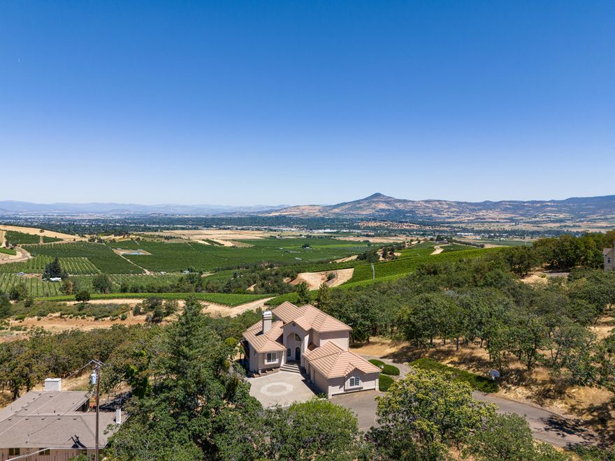 Priced to Sell VIEW home! 3726 SQ FT Home + 1700 SQ FT Art Studio or Hardship Home w/county approval. NW Contemporary style stucco home w/tile roof & stunning valley, sunset & vineyard views! Main home is approx. 3726 SQ FT. DBL door entry, marble entry, curved staircase, lg living rm w/fireplace and floor to ceiling windows, formal dining w/crown molding, wet bar & French door to a deck. Kitchen island, walk in pantry & breakfast rm. Upper-level w/dbl doors to primary suite w/amazing views, dual sink vanity, jetted tub, lg marble shower & walk in closet. Lower-level w/ great family rm, floor to ceiling rock fireplace, wet bar, indoor sauna & hot tub with windows overlooking the views. 3 car garage w/separate office room just off the laundry room. The old original home would make a perfect Art studio, Office or Hardship Home w/approval from county w/4 bdrms, 2 baths and approx. 1700 SQFT with open beam ceilings in living rm.