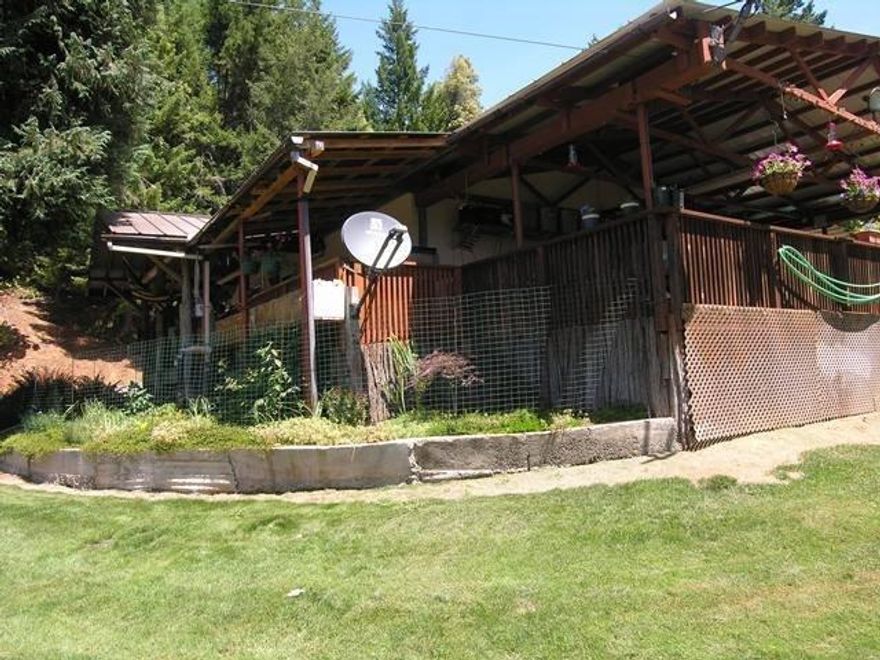 Private in Agness, Oregon is this very unique property with lots of nature beauty! This property is carved into a hillside on a private road with views of the trees across the valley. This manufactured home has a built on mudroom addition which totals 300 sq ft. There is also a separate office/computer room or could be a guest room? The stone hearth is made from rock from the Rogue River. Off the mudroom is Koi pond with large Koi! The home is 3 bedrooms and 2 full baths, plus in addition a rustic sleeping cabin with shower and bath. (not in square footage). It has a big vegetable garden with raised beds, plus established strawberries, asparagus, blueberries, etc. The well is high producing at approximately 20 GPM per seller and very sweet water! The shop is approx. 2400 sq ft and wired for both 110 and 220 power. Also, a loft for storage. This could be a wonderful retreat or full time residency.