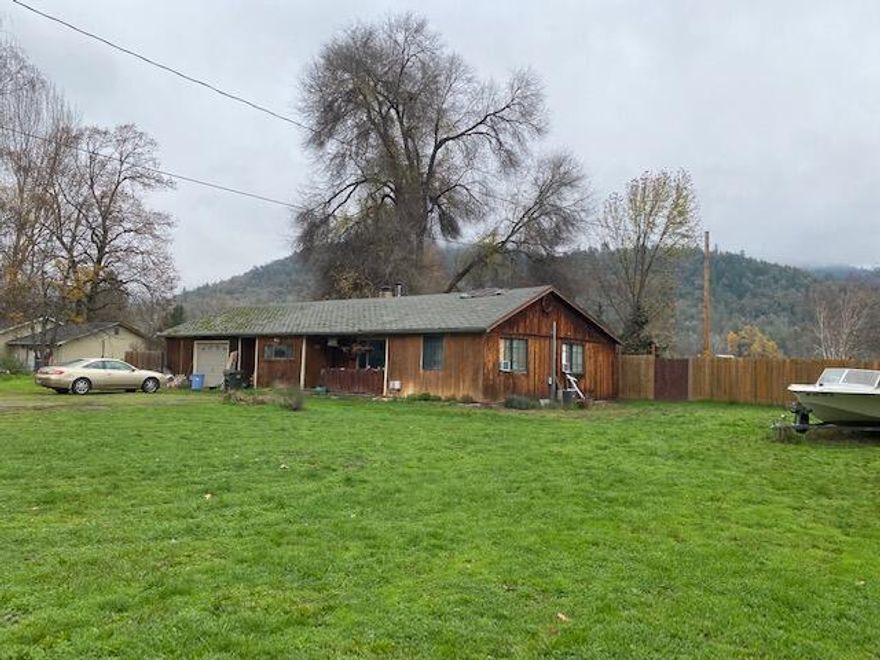 This is a great parcel of usable level land zoned EFU (Exclusive Farm Use). Right across the street from the mighty Rogue River with great mountain views! This 2.63 acre property is completely fenced and has been used for medicinal marijuana in the past. There are also some veggie garden beds that have produced wonderfully in spring and summertime! There are several out buildings, plus a detached bedroom, bath & shower that is behind the garage. There is a great chicken coop & the chickens can stay with the property! The house has a large updated bathroom with laminate wood floors, toilet & sink. There is a sizable laundry room, kitchen, dining area and living room. Although this property is in need of updating, it's been livable but in need of a rehab! Cash Buyers Only, the house will not qualify for a loan at this time.