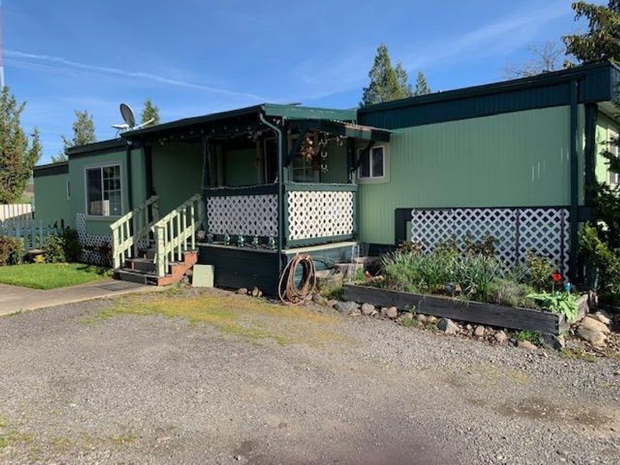 Low cost living in Ashland is possible. This 3 bedroom, 2 bath home in popular all-ages Bear Creek Mobile Park has a great location in the park. The space is large with a carport/workshop, shed & huge backyard. Guest parking & mail boxes are just across the driveway. A cute front porch has sliding doors into the dining area & kitchen. The kitchen cabinets have nice, upgraded wood fronts. The living areas & bedrooms have laminate floors. The floor plan is split with one bedroom & bath in the front of the home. The other two bedrooms are in the back of the home with tiled floors in the laundry area & the other bathroom in between. Out the backdoor is a storage shed & covered deck. The living room sports a 12'X7' tip out that adds useful space. Space rent is $400/month & includes water, sewer & garbage. You'll find lovely views of the mountains. There is a large, grassy area near the manager's space that is great for picnics & play time. Close to town but with a country feel.