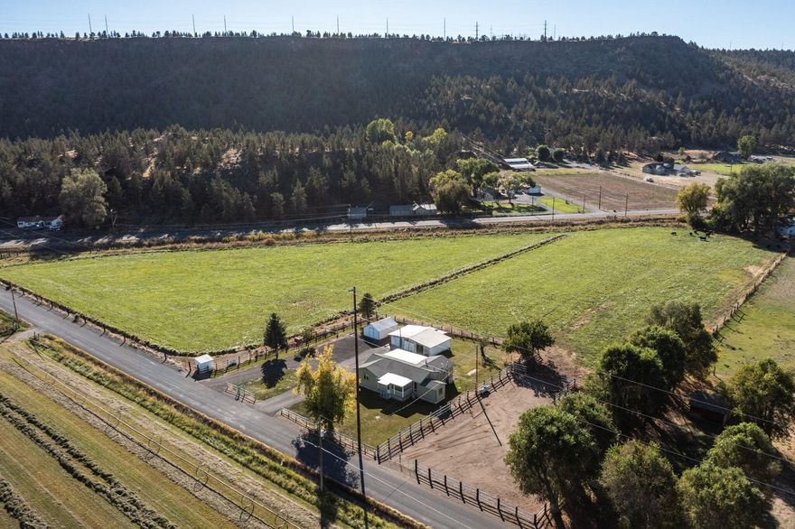 Rare opportunity! Peaceful country living w/ irrigation rights & horse amenities. Escape to this charming 2 bed, 1 bath home w/ bonus room, nestled on 6.6 acres w/ valuable irrigation rights, surrounded by mature trees & amazing views. Whether you're looking for a hobby farm, horse, cattle, or alpaca property, or a quiet rural retreat, this one checks all the boxes. Enjoy easy flood irrigation that keeps the entire pasture lush & green, perfect for grazing or gardening. Land is fully fenced, complete w/ large workshop, corral, stable w/ 2 stalls, & hay storage. The home features covered front porch w/ beautiful views of surrounding farmland, ideal for morning coffee or sunset unwinding. Inside, the layout offers cozy living spaces & versatile bonus room. Large workshop provides ample space for tools, projects, or storage, making this property as practical as it is peaceful- & even comes w/ a riding mower! Located in a quiet rural setting w/ room to roam.