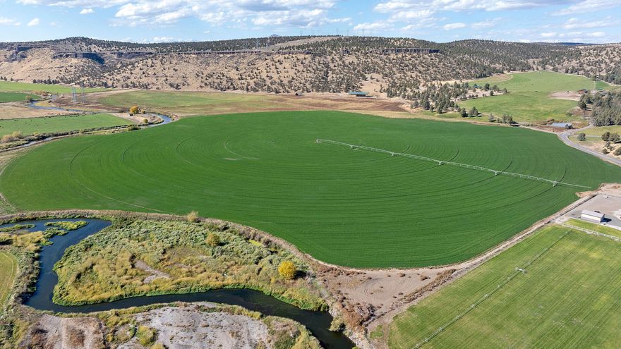 King Ranch on the Crooked River is a rare 824±-acre Central Oregon property blending productivity, recreation, and natural beauty. With 293± irrigated acres and 3± miles of Crooked River frontage set against the Cascade Mountains, it offers a serene haven for those seeking a family compound, private retreat, or working ranch. The ranch supports 120 acres of alfalfa, 80 acres of grain hay, and 110 acres of pasture, yielding 900-1,200 tons of hay annually through efficient irrigation systems. Outdoor enthusiasts enjoy fishing, 2 LOP tags, and nearby recreation. The property includes a 1,324 sq. ft. home with 2 bedrooms, 2 baths, and a loft, plus barns, shop, sheds, cattle and calving facilities, and an arena. With two additional buildable parcels (permits in place) and convenient access to Prineville (10 min) and Redmond (15 min), King Ranch offers a unique blend of privacy, productivity, and scenic tranquility—a true Central Oregon gem.