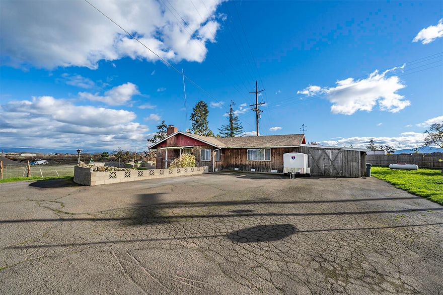 Incredible opportunity!!! Do not miss out on this chance to own an amazing farm property! Sitting on two tax lots, total of 3.15 acres, with incredible views of the surrounding mountains. This 3 bed 2 bathroom home allows you to live in the Country, but still have access to town with a short drive!  The home features 1,768 SqFt of living area, including a large living room with a wood burning fireplace, a kitchen with multiple sinks for convenience, large pantry & plenty of storage options! Enjoy country living at its finest with over 3 acres of land, perfect for gardening, animals, or outdoor entertaining. Property has its own well & septic system, and the land also features a couple outbuildings - Perfect for storing tools and equipment.