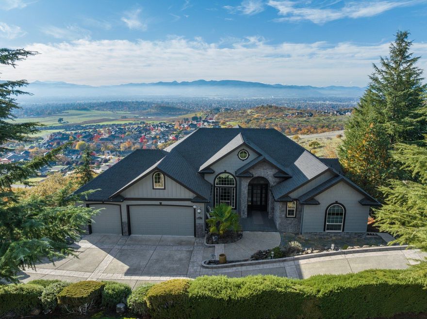 Best VIEWS in Southern Oregon! This 5 bedroom, 3 bathroom, Plus Office & Movie Theater, 4,500 SQFT luxury home provides a perfect balance of space and sophistication. The kitchen is a culinary sanctuary, featuring granite counter tops with appliances that elevate your cooking and entertaining experience. The open floor plan, 14' coffered ceilings, and expansive windows create a luminous ambiance, providing breathtaking views with tons of natural light! The living room features radiant heated tile floors, complemented by the fireplace and custom finishes that add a luxury feel throughout. Whether you're enjoying the extensive views from every room, sitting on the upper or lower deck enjoying coffee, or relaxing in the indoor pool/spa, this home seamlessly has it all.  This home offers a perfect 2-family setup or potential short term rental opportunity, with the downstairs having its own separate entrance and kitchen! Don't miss the opportunity to make this incredible place your own.