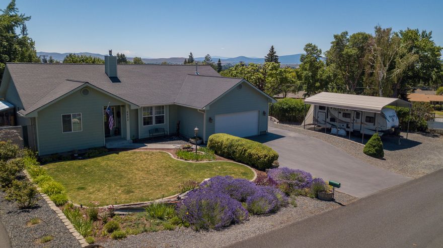 Well maintained modern home features open floor plan and vaulted ceilings.  Kitchen appeals to cooking enthusiasts desiring ample counter space.  Primary bedroom separated from secondary bedrooms enhances privacy.  Oversized 2 car garage includes overhead storage racks.  Paved extra parking and a 10' high detached RV shed with power and dump.  Fenced backyard with patio, water feature, buried drip system and manicured landscaping.  Enjoy the views including Mt Shasta and the city lights from this turnkey home.