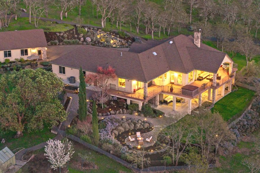 Set in the foothills of E. Medford, this elegant, close-in 79.67 acre property offers breathtaking 180 degree Rogue Valley views. The 4,104 sq. ft. rustic contemporary home boasts an open floor plan, vaulted ceilings, hickory floors, and two stunning stone fireplaces. Designed for comfort and entertaining, it features 4 bedrooms, 4 baths, an office, and a chef's kitchen with high-end finishes. Expansive windows flood the home with light, while 1,300 sq. ft. of decking offers space for outdoor living with a hot tub and sunset views. Meandering gardens, front and back water features, raised beds, fruit trees, greenhouse and a divine fire pit area enhance the stunning setting. The flexible layout is ideal for multi-generational living. A gated drive leads to a finished 3-car garage plus a heated 4-car garage/shop. In this park-like setting, wildlife and nature abound, yet amenities in Medford are only 10-15 minutes away. A fabulous home blending luxury, privacy, and convenience.