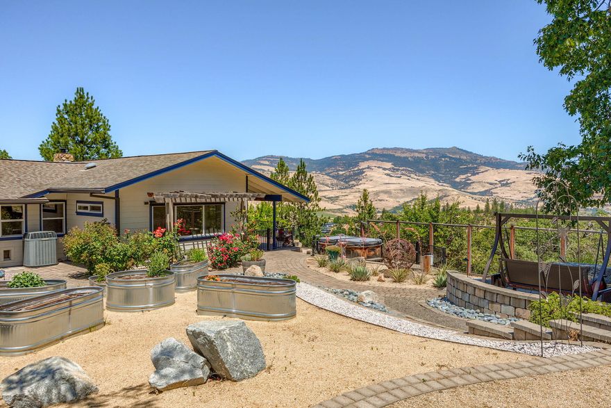 Discover this 2,416 sq ft single-level gem on over 12 acres in one of Ashland's most desirable neighborhoods just minutes from the downtown. Enjoy panoramic views of the surrounding hills from this elegant home featuring an updated kitchen with soapstone countertops and vaulted ceilings in both the kitchen and living room. Enjoy sustainably harvested myrtlewood and hickory flooring, along with custom built-ins. The primary bedroom offers an ensuite bathroom with a luxurious walk-in tile shower, while the hall bathroom boasts a curbless walk-in tile shower. An oversized 4th bedroom provides added versatility. The attached studio, with vaulted ceilings, is perfect for an art studio, office, or home gym. Outdoor living is a delight with an extensive patio and fully fenced gardens. A detached workshop/garage completes this exceptional property. Combining elegance, comfort, and modern amenities, this home offers a perfect retreat. Don't miss the chance to own this unique piece of paradise!