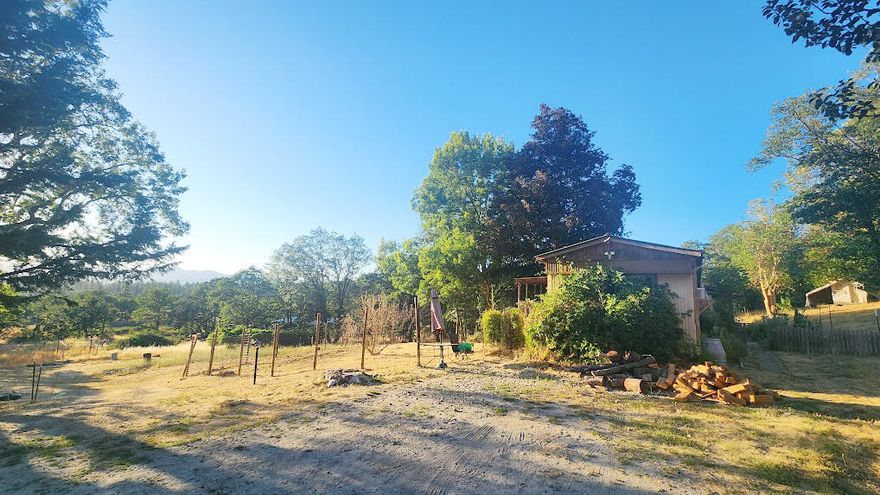 MOTIVATED SELLER!

Mountain views and gently sloped, usable acres blend privacy, function, and beauty in this rural retreat. This property feels secluded, surrounded by natural beauty, yet sits just minutes from everything: 8 minutes to Merlin, 12 to downtown Grants Pass. Directly next to North Valley High School (tucked behind a hill for privacy), hike up and watch live games. Enjoy spectacular sunsets and views that change with the seasons, from your own front porch. Irrigated and fenced gardens, mature grapevines and herbs, and a natural spring support self-sufficiency. A newer metal roof, newer kitchen stove, cozy wood stove, front and back patio spaces, and a fire pit add comfort and charm. The home is rustic but fully functional: no frills, no staging, just solid, straight-forward infrastructure rarely found at this price point. Three outbuildings provide room for projects, storage, or creative use. A rare find ready for easy living.

DO NOT STOP BY WITHOUT APPOINTMENT