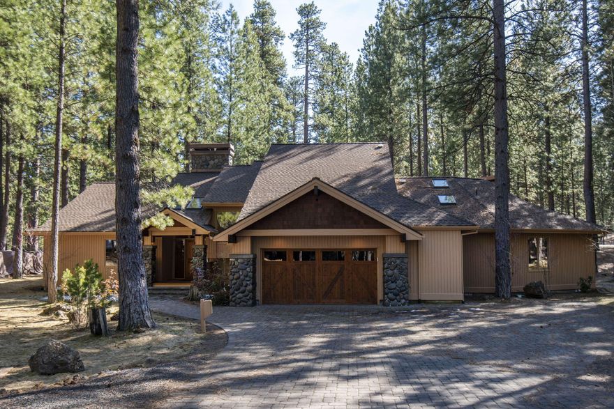 Classic Northwest crafted home on a large half acre lot backing to National Forest land with mature ponderosa pines! The privacy, setting and location of this home is truly unmatched!  One step inside and you will see and feel the quality of construction, materials and woodwork used throughout this home. Features include numerous stone & wood accents, high vaulted ceilings, two gorgeous river rock fireplaces, one with gas assist, open great room floorplan, oversized wood wrapped windows and numerous skylights, gorgeous tongue & groove hardwood flooring, SS appliances including dual ovens, large butcher block kitchen island with prep sink, wood paneled family room with wet bar, sink and refrigerator, main level primary suite & second primary suite upstairs, loft area with built in desk, cabinets, and shelving and an oversized laundry room with a laundry shoot.  Other features include, wine room, garage storage room, garage workbench, expansive back deck, built in BBQ and newer hot tub.