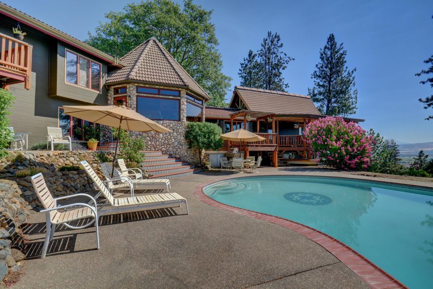 Perched in the Western hills overlooking the Rogue Valley,  North Star Ranch is sure to impress. Upon entry, you will begin to experience the ''lodge feel'' of this expansive, yet comfortable, custom home. The views from the great room (and almost every other room) are breathtaking from the wall of windows framed by the 25 ft. pine ceiling. The Chef's kitchen is ready to impress with hand milled maple cupboards, slab granite countertops, sub zero fridge & freezer, commercial 6 burner stove, custom hood/mantle, and detached butler's kitchen. The main suite has a private deck, seperate den, cedar lined walk in closet, & bathroom with dual vanities, jetted tub and stand alone shower. The expansive downstairs could be perfect for a two family or split living situation with private entry. The manicured backyard features a pool, waterfall and hot tub surrounded by many decks and patios to relax on. There is also a barn w/3 stalls for your animals and a lighted sports court for the kids