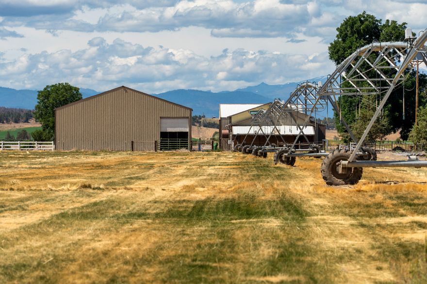 This 35-acre pivot-irrigated farm offers productive ground for hay or crops, stunning Cascade Mountain views, and a beautifully maintained home. Recently painted and thoughtfully updated, the 2-story residence features a bright kitchen with modern finishes, a cozy family room, private office, and an upgraded primary suite with fireplace, spa-like bath, and serene vistas. Step outside to a landscaped yard with mature trees, paved patio, soothing water feature, and fire pit for evenings under the stars. Three impressive outbuildings provide exceptional utility: a 2,668 sq. ft. shop with multiple bays, RV hookups, insulated workshop, and bathroom; a 2,328 sq. ft. utility building for storage or equipment; and a 1,440 sq. ft. hay cover. With room for productivity and space to relax, this property blends farm functionality with rural lifestyle appeal, all just five minutes from town.