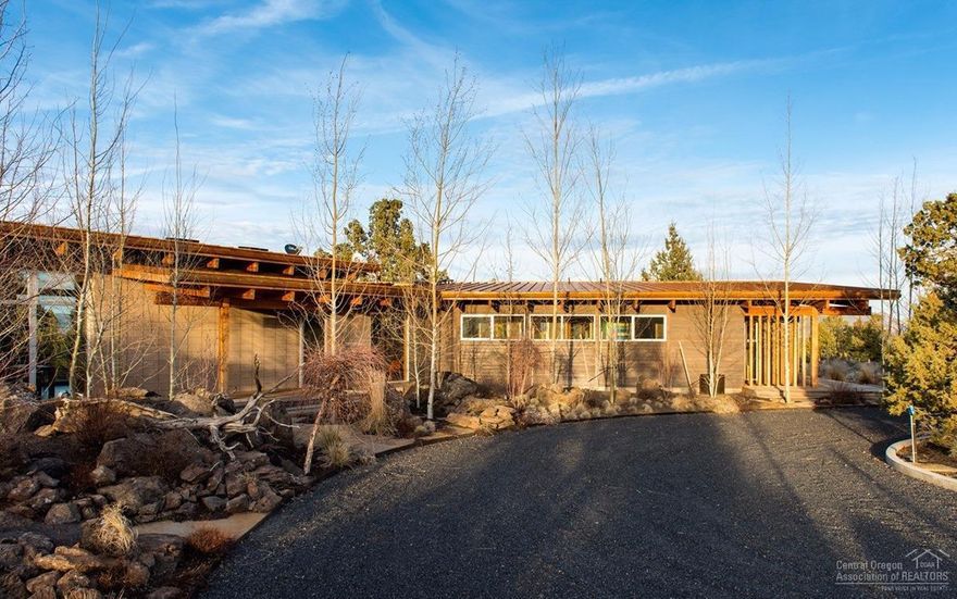 A rare, custom, gem of a home surrounded by a forest of trees in the front and open in the rear to enjoy the Smith Rock and Cascade Mountain Views all around you. A private setting on 12+ acres above the Deschutes River Canyon and trails. This single level, contemporary style home has 2 Master Suites on each end with a 3rd BR in the center. Has a large, stone Rumford Fireplace, native landscaping, large lawn area and 3,804 Sq. Foot additional Garage/Studio/Shop plus covered carport.