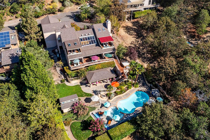 Live like you're in a private Palm Springs resort in this stunning Pagnini home with panoramic valley views on a private 0.65-acre lot in E Medford. The 3581-sqft home blends indoor and outdoor living for year-round enjoyment. The open-concept main level features a great room with a dining area, private balcony, and a chef's kitchen with soaring ceilings, a large island, built-in dining booth, and premium appliances like a Subzero fridge, Wolf double oven, and Viking gas range. The study wing includes an office with ensuite bath, marble floors, gas fireplace, and private balcony. Downstairs, a spacious living area with a wet bar separates the primary and guest suite wings, all with access to the covered patio. Resort-style amenities include an in-ground pool, new hot tub, huge covered outdoor kitchen with pool bathroom, and beautifully manicured grounds. The 5-car garage offers ample storage. Plus, there's a finished garden shed and large storage room.