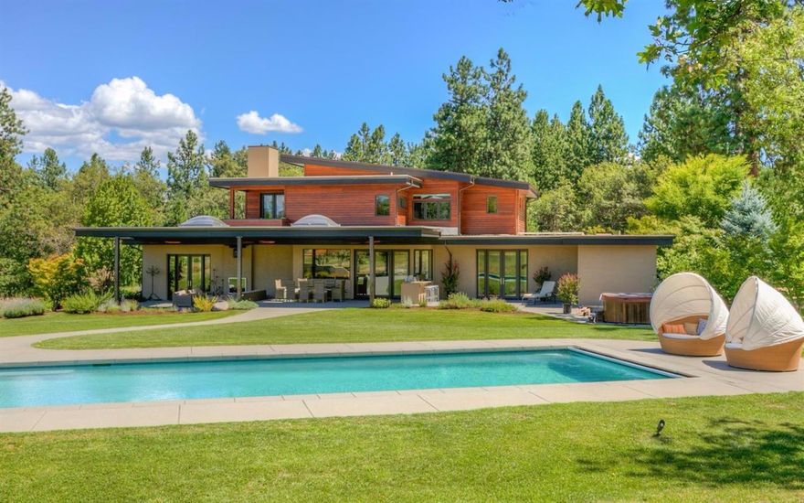 Experience the feeling of serenity in this gracious estate. Enter through the 2 story foyer & immediately feel at home with a wall of windows bringing the outdoors inside to you. Large living room with Brazilian cherry wood floors with a see through gas fireplace. High tech lighting and a very sophisticated sound system. Expansive gourmet kitchen showcases modern technology. Viking 8 burner gas stove, built-in stainless steel refrigerator & custom cherry cabinets. Generous main level master suite with views & spa quality master bathroom. Upstairs are 3 addt'l bedrooms with bathrooms & balconies. Fantastic workout room w/ mirrored wall, 3/4 bath & sauna. Outdoor sitting area offers a gas fireplace & a granite countered built-in BBQ w/refrigerator. Nicely appointed tasting room. Spacious media room. Beautiful solar heated pool with electric cover, separate outdoor sitting area & speakers. Great barn with 2 vast sliding barn doors, skylights, greenhouse, workshop, art studio and a loft