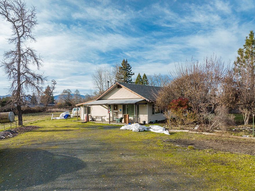 Cool Cottage-Style Home on 2.21 Acres of Level and Useable Irrigated Land just on the Edge of Town! Enjoy the benefit of County Zoning and Taxes, with the City Limits literally across the Street! The Home itself is a 2-3 Bedroom, 2 Bath, with a Cutesy Main Living Area and Country Kitchen. The Home offers a Surprisingly Comfortable and Welcoming Floor Plan, and is in overall Good Condition. The Property offers a Nice Shop with Carport, and there are a couple of  Additional Outbuildings. The Land here is Level and Useable, perfect for Animals and Garden. Enjoy Established Fruit Trees, Grapes, Blueberries, ornamentals, and other Similar Amenities. There are some unfinished areas in and around the Home, and it could benefit from some Cosmetic Upgrades and Updates, but overall this is a Neat Home and Property, with Future Potential right on the edge of Development!