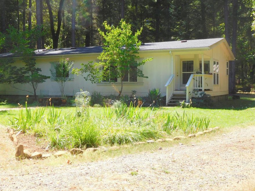 Home Sweet Home! Lovely mfg. home in a great setting with beautiful trees, on all level 5 + acres. The home offers all most new interior paint in every room, composite wood floors, bright cheery kitchen with a breakfast nook. Lots of cabinetry and lots of light. Good sized living room/ com. dining room. There is a den/office (possible use as 3rd bedroom) plus master bedroom with vaulted ceilings and walk in closet. Master Bath, is spacious and offers tub/shower comb.. 1 other bedrooms are good sized as well. Laundry has exit door to back yard activities. Det. garage, has workbench and lots of room for vehicle, etc. Owner says well is excellent and no treatment system necessary. Property is nicely wooded and setting is semi-pvt for the home/garage. Utility shed next to garage. Gate at entrance to prop. Home sits back off the public road. All this and move in ready, and only l0 mins or so to all town conveniences and schools, etc.