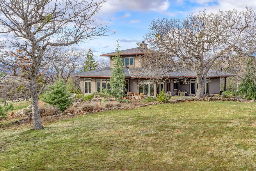 Custom, one owner Prairie style home in the sought after, close-in rural location near Emigrant Lake. Fabulous architecture with the comfort & warmth of multiple woods & stone throughout including tan oak, cherry & fir. Open kitchen w/ plentiful storage, granite countertops & fossil inlayed tiled backsplash. Curved walls & recessed LED lighting add to the artistic flare of this immaculate home. The great room has a wall of windows overlooking the professionally landscaped gardens & courtyard. It also boasts 10 foot ceilings w/ exposed beams, an efficient woodstove w/ slate surround. French doors in the dining room lead to the south patio. The primary owner's suite features a travertine bathroom with dual sinks, spacious shower & walk-in closet. Additional main level suite is nicely separated & located on the other side of the home. Upstairs is a light-filled office; great for overflow guest space. Detached two car garage with workshop. Strong well, views in every direction. A Must See!