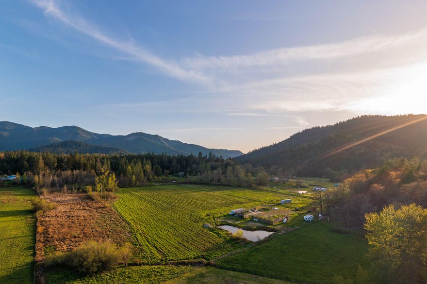 Welcome to Fish Hatchery Road, a prime homesite opportunity to enjoy the rural lifestyle. Nestled in a valley surrounded by mountains, this property has a truly picturesque setting. Totaling 10.86 acres, the RR-5 zoning may allow for the possibility of a second homesite. The wide, established gravel driveway leads you to the property, which is a wonderful place to live the rural lifestyle. The homesite is set back from Fish Hatchery Road, making for a private setting, but is only 2 miles from the charming town of Wilderville and 11 miles from Grants Pass. With easy access, large open fields, level topography, 9.2 acres of irrigation rights (Wilderville Irrigation Improvement District), and an on-site pond, there are many options for your future farm or rural estate.