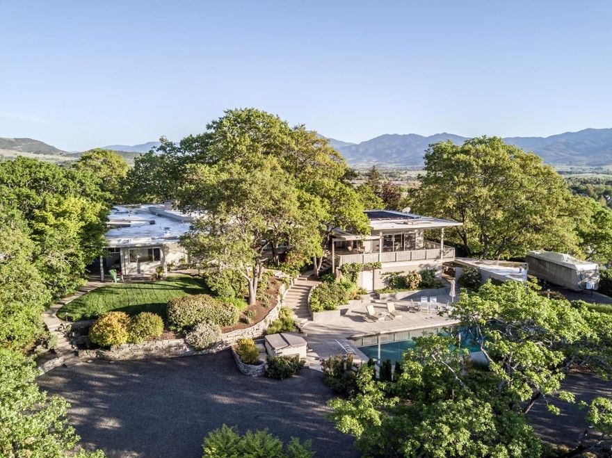 Top of the Hill views from this Amazing Mid Century Modern home & Estate overlooking Medford & the Rogue Valley! Architecturally designed on over 2 acres in the heart of East Medford, this 4200+ sq ft home has views overlooking the vineyards, valley lights & surrounding mountains. A single story home, perfect for entertaining, w/beautiful easy care landscaping, large shop, abundant parking, ig pool w/auto cover, & a separate finished living area w/ views, perfect for a pool house, bonus room, or guest suite. 3 bedrooms, all ensuite, a large breathtaking living room with a wall of 10 ft windows, light, bright kitchen w/designer appliances, hardwood, heated marble floors & so much more! Totally fenced & security gated, this is a One of a Kind Property!